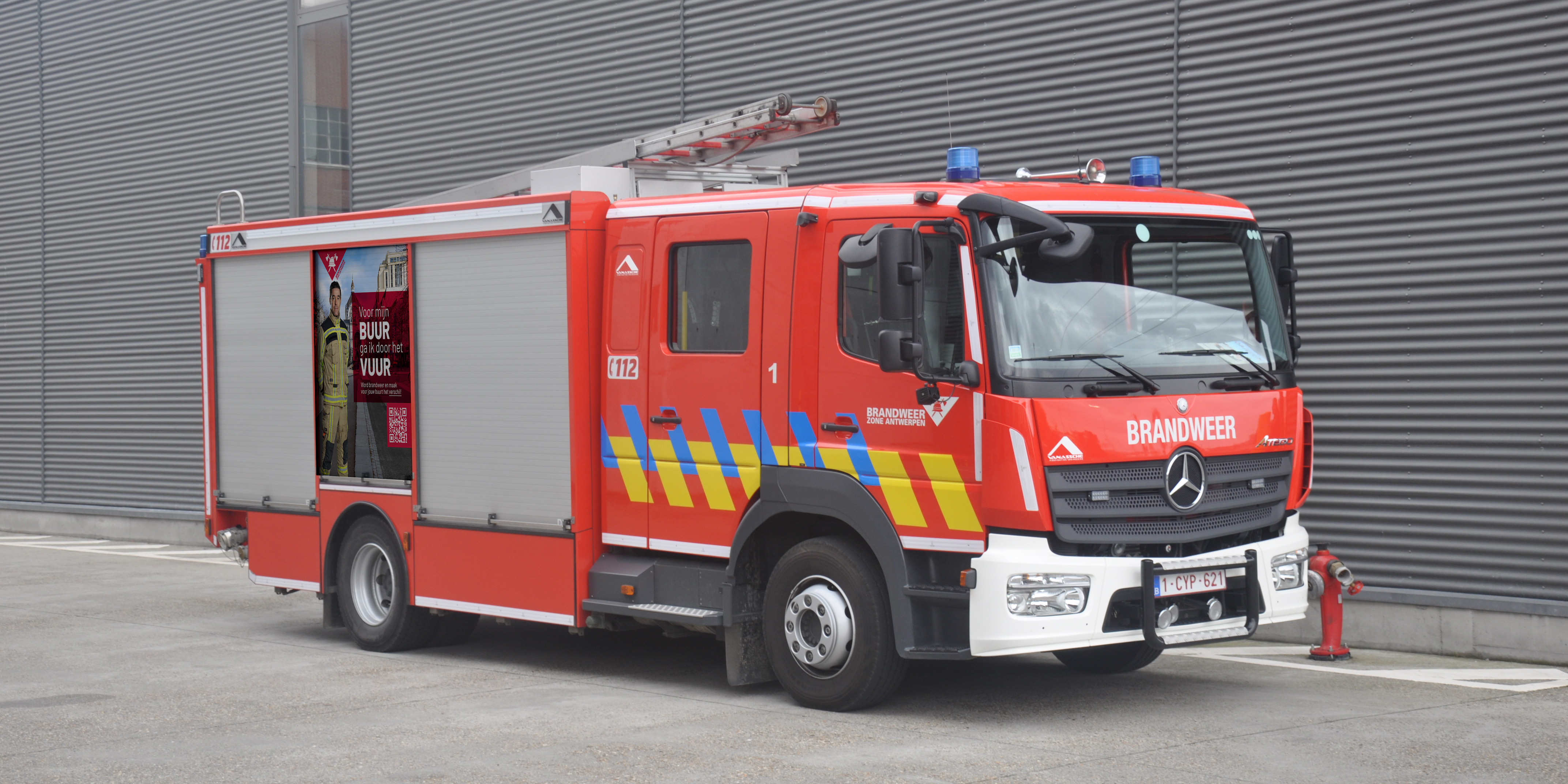 Brandweerwagen met op de rolluiken een sticker van het campagnebeeld met een brandweerman Brandweerwagen met op de rolluiken een sticker van het campagnebeeld met een brandweerman